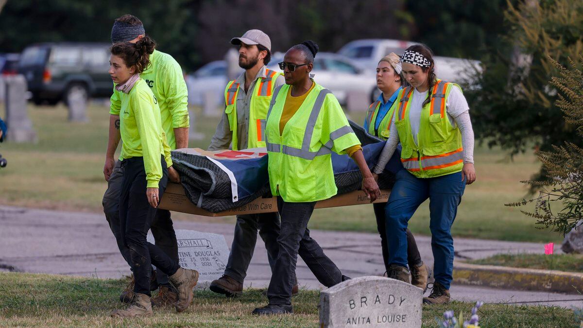 Researchers and burial oversight committee member Brenda Alford carry the first set of remains...